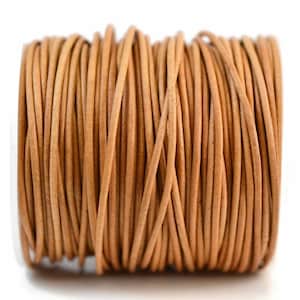 May include: A spool of natural-colored leather cord. The cord is tightly wound, revealing a cylindrical shape. The leather appears to be a light brown color, with a slightly textured surface. This cord is suitable for jewelry making and crafting.