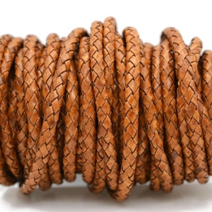 May include: A spool of brown leather cord, braided in a diamond pattern. The cord is tightly wound and ready for crafting projects.