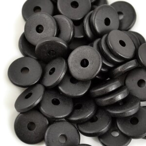 May include: A pile of black wooden beads, each bead is a flat disc with a hole in the center.