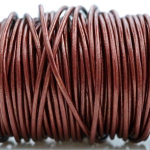 May include: A spool of brown leather cord. The cord is tightly wound and appears to be made of a smooth, flexible material. The color is a rich, warm brown, and the cord is likely used for jewelry making or crafts.