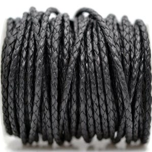 May include: A spool of black braided leather cord. The cord is tightly woven, creating a textured surface. The dark color and braided design suggest its use in jewelry making or crafting projects.