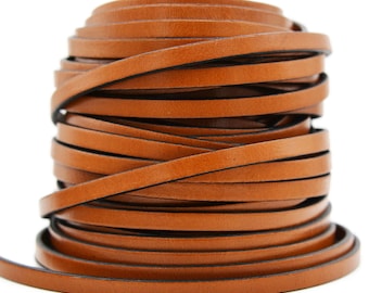 May include: A continuous coil of flat, tan-colored leather cord. The strip features a smooth, matte surface with dark, finished edges, wound into a cylindrical stack that tapers slightly toward the top, showcasing a consistent width throughout.