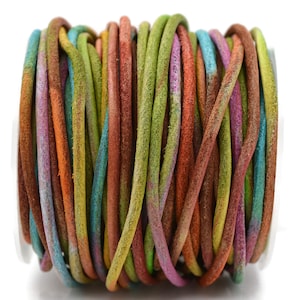 May include: A spool of colorful leather cord in shades of brown, orange, green, blue, and purple. The cord is tightly wound, showing the texture and variation of the dyed leather. This craft supply is suitable for jewelry making and other DIY projects.