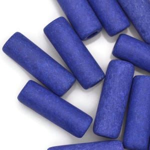 May include: A group of blue ceramic cylinder beads with a rough, textured surface. The beads are scattered on a white background.