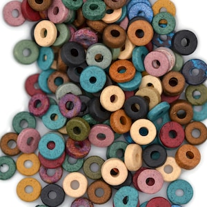 May include: A collection of colorful, round wooden beads in various shades of blue, green, pink, brown, and black. Each bead has a hole in the center. The beads are scattered on a white surface.