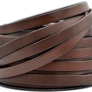 May include: A stack of dark brown leather strips, tightly coiled. The strips are thin and flat, with a smooth texture and a slight sheen. The leather appears to be of high quality, with a rich, warm color. The strips are likely used for crafting or jewelry making.