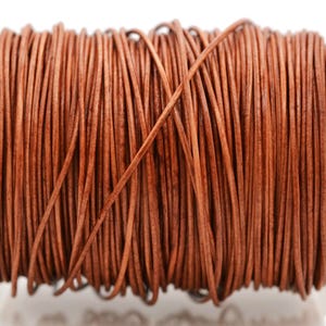 May include: A spool of round, medium-brown leather cord wrapped tightly in multiple vertical layers. The cord has a smooth, consistent texture and a natural, earthy tone, wound around a clear plastic cylindrical core for organized storage.