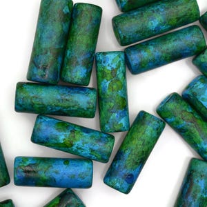 May include: A collection of wooden cylinder beads with a blue and green marbled pattern.
