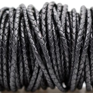 May include: A spool of black braided leather cord. The cord is tightly woven, creating a textured surface. The dark color and braided design suggest its use in jewelry making or crafting projects.