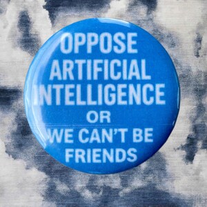 Pode incluir: Um bot&atilde;o redondo azul com texto branco: "OPPOSE ARTIFICIAL INTELLIGENCE OR WE CAN'T BE FRIENDS." O bot&atilde;o est&aacute; sobre um fundo texturizado com nuvens cinzentas e brancas.