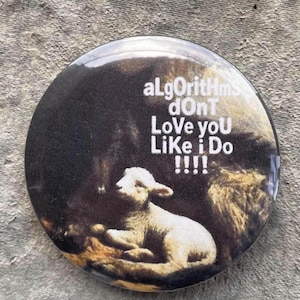 May include: Round button with a lamb illustration and the text "aLgOrIthMs dOnT Love yoU Like i Do !!!!" The button has a glossy finish and a dark background with a lamb in the foreground.