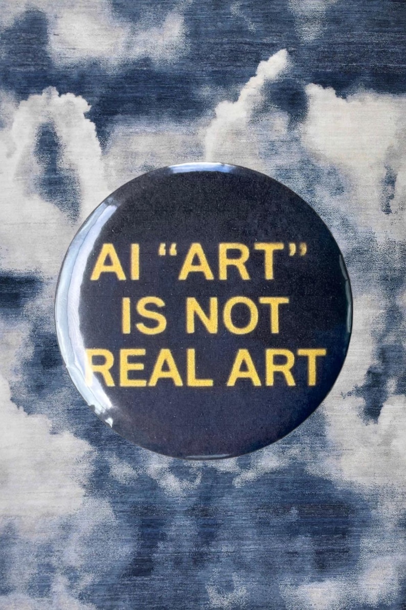 Pode incluir: Um bot&atilde;o preto com o texto "AI 'ART' IS NOT REAL ART" em amarelo. O bot&atilde;o est&aacute; sobre um fundo de um padr&atilde;o de nuvens azuis e brancas.