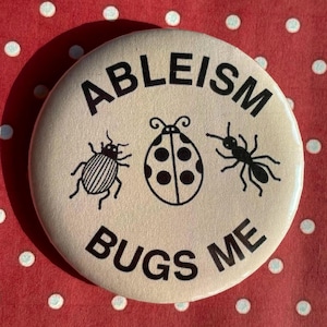 Può includere: Un bottone rotondo bianco sporco con le parole nere "ABLEISM BUGS ME", che circondano tre illustrazioni di insetti neri: uno scarabeo, una coccinella e una formica. Lo sfondo è rosso a pois bianchi.