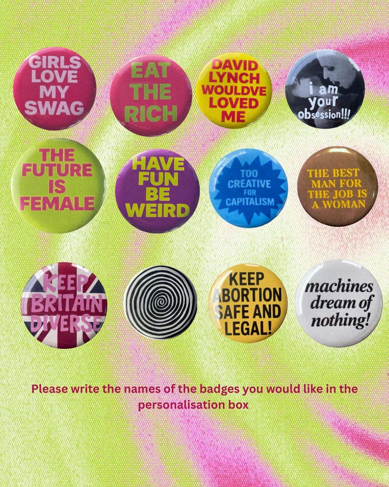 K&ouml;nnte beinhalten: Eine Sammlung von elf runden Ansteckbuttons mit verschiedenen Slogans und Designs, darunter Texte wie Girls Love My Swag, Eat The Rich, David Lynch Wouldve Loved Me, I Am Your Obsession, The Future Is Female, Have Fun Be Weird und weitere.