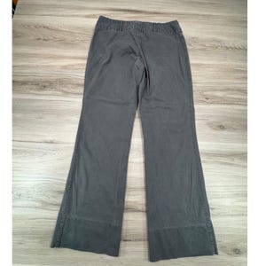 May include: Gray wide-leg pants with a high waist. The pants have a classic design with a button and zipper closure, belt loops, and pockets. The pants are made of a durable fabric and are suitable for various occasions.