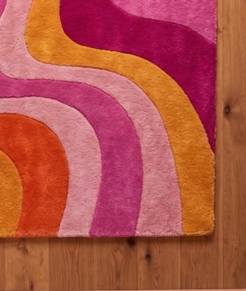 May include: A rectangular area rug featuring a series of wavy, curved stripes in vibrant shades of orange, light pink, magenta, and deep pink. The rug has a thick, plush texture and is arranged in a repeating pattern of flowing, organic lines.
