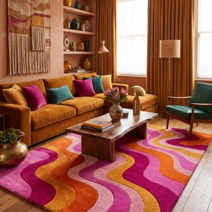 May include: A rectangular area rug featuring a repeating wavy pattern in vibrant shades of hot pink, light pink, orange, and mustard yellow. The rug has a plush, textured surface and is positioned on a light-colored wooden floor in a living room.