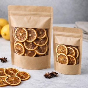 Könnte beinhalten: Zwei Kraftpapierbeutel mit Klarsichtfenstern, gefüllt mit getrockneten Orangenscheiben. Die Beutel sind unterschiedlich groß und mit einem Reißverschluss verschlossen. Sternanis und lose Orangenscheiben sind um die Beutel herum verstreut.