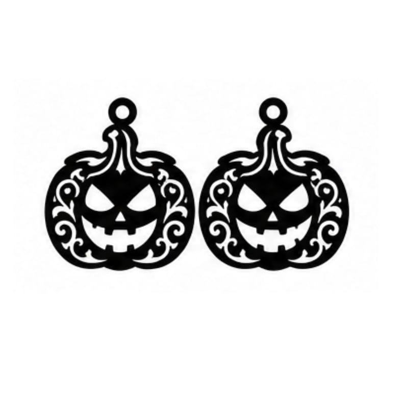 Op de afbeelding: Een paar platte, zwarte pompoenvormige hangers met ingewikkelde, wervelende filigraan uitsparingen. Elke pompoen heeft een jack-o'-lantern gezicht met driehoekige ogen, een brede, getande grijns en een ronde lus aan de bovenkant.