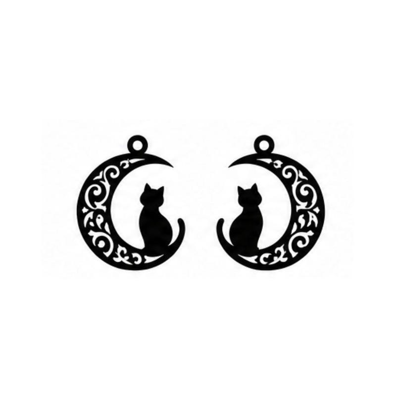 Op de afbeelding: Een paar zwarte, ronde hangers met het silhouet van een kat die in een halve maan zit. De maan is versierd met ingewikkelde, wervelende filigraan uitsparingen. Elke hanger heeft een kleine ronde lus aan de bovenkant om op te hangen.