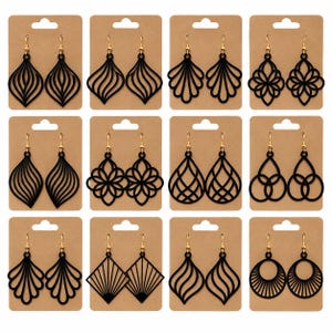 May include: A collection of twelve pairs of black laser-cut earrings with gold-toned metal hooks, each pair displayed on an individual brown cardboard backing card featuring various geometric, floral, and abstract cutout patterns.