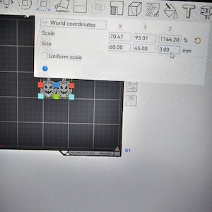 Op de afbeelding: Een digitale interface toont een 3D-modelleringsscherm met een werkbankweergave. Het display bevat een pop-upvenster met wereldco&ouml;rdinaten, schaalinstellingen en afmetingen van 60,00 mm bij 45,00 mm bij 3,00 mm voor een pompoengrafiek.