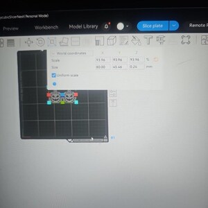 Op de afbeelding: Een computerscherm met de AnycubicSlicerNext software-interface en een 3D-model van twee pompoenen op een raster. Een pop-upvenster toont wereldco&ouml;rdinaten met een afmeting van 80,00 x 45,46 x 0,24 mm en een uniforme schaal van 93,96%.