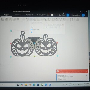 Op de afbeelding: Een computerscherm met de AnycubicSlicerNext software-interface met twee identieke grijze pompoenvormige ontwerpen. De software toont een rode foutmelding die aangeeft dat een object buiten de rand van de printplaat ligt.