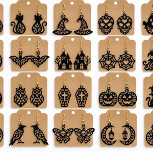 Op de afbeelding: Een collectie van twintig paar zwart lasergesneden acryl oorbellen met diverse Halloween-thema ontwerpen, waaronder pompoenen, katten, schedels, geesten, vleermuizen, spookhuizen, spinnenwebben, heksen, uilen, doodskisten, bomen, raven, vlinders en lantaarns.