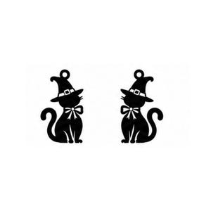 Op de afbeelding: Twee identieke zwarte silhouetten van katten die puntige heksenhoeden dragen met gespbanden en strikken om hun nek. Elke katfiguur heeft een kleine ronde lus aan de bovenkant van de hoed, wat suggereert dat ze bedoeld zijn als bedels.