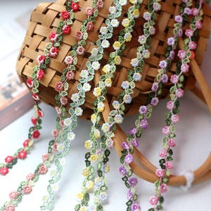 Può includere: Assortimento di passamaneria di pizzo floreale con delicati disegni di fiori e foglie in vari colori, tra cui rosso, rosa, giallo, viola e verde.