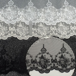 Peut inclure: Une bordure en dentelle blanche et noire pr&eacute;sentant un motif r&eacute;p&eacute;titif de silhouettes de ch&acirc;teaux dans des arches festonn&eacute;es, agr&eacute;ment&eacute; de petits n&oelig;uds et d'&eacute;toiles. La broderie complexe est sur un tissu en maille transparente festonn&eacute;.