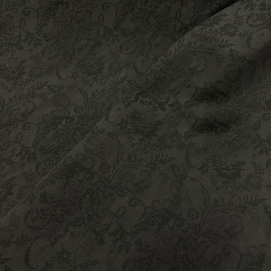 Puede incluir: Tela de color carbón oscuro con un detallado estampado floral y paisley. La tela tiene un brillo sutil, con el diseño ligeramente más oscuro que el color base. Los pliegues crean sombras, realzando la textura y la profundidad del diseño.