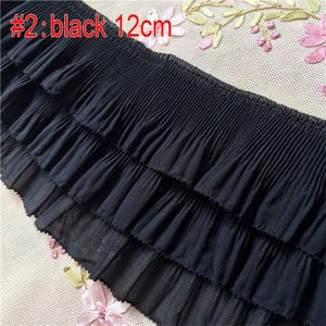 May include: Black ruffled trim with three layers of pleats. The trim is 12 cm wide.