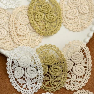 May include: Assortment of oval-shaped lace appliques in white, beige, and gold. The lace features delicate floral designs.