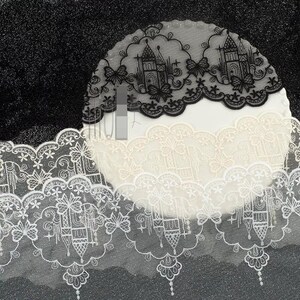 Peut inclure: Une bande de dentelle d&eacute;corative pr&eacute;sentant un motif r&eacute;p&eacute;titif de silhouettes de ch&acirc;teaux, de papillons et d'&eacute;toiles. La bordure est disponible en noir et blanc, avec un bord festonn&eacute; et des broderies complexes sur tout le tissu.