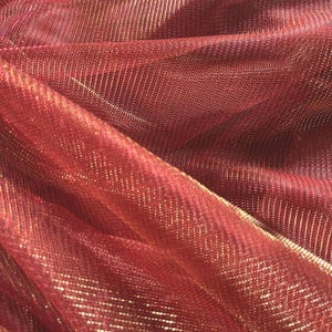May include: Red mesh fabric with gold metallic threads woven throughout. The fabric has a subtle sheen and a soft, drapey texture.