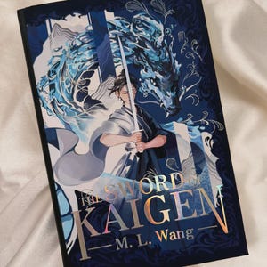 May include: A hardcover book titled The Sword of Kaigen by M. L. Wang. The cover features a dark blue background with a central illustration of a person holding a sword, surrounded by a swirling blue water dragon design and metallic gold lettering.