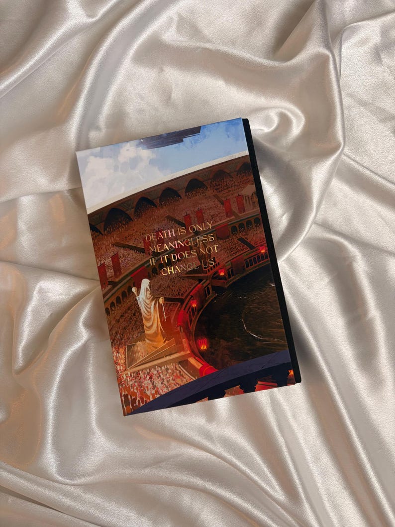 May include: A hardcover book with a colorful illustration on the cover. The image depicts a figure in a white robe, standing before a crowd. Text on the cover reads: "DEATH IS ONLY MEANINGLESS IF IT DOES NOT CHANGE US."