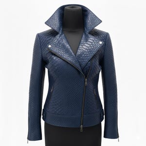 Op de afbeelding: Een marineblauwe leren jas met een slangenleertextuur. De jas heeft een reverskraag, een asymmetrische ritssluiting en meerdere zakken. De mouwen hebben ritsen bij de manchetten. De jas wordt getoond op een zwarte mannequin.