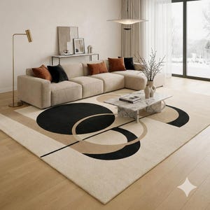 May include: A modern living room featuring a beige sectional sofa with several throw pillows in shades of brown and black. A large area rug with a geometric design in black, beige, and tan covers the floor. A marble coffee table and a gold floor lamp complete the decor.