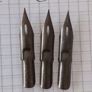 May include: Three silver-colored calligraphy nibs with a pointed tip and a small hole in the center. The nibs are labeled "No.2" on the bottom.