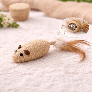 May include: A beige cat toy in the shape of a mouse, constructed from woven material. It features brown ears, black eyes, and a feathered tail. The toy is designed to encourage play and may contain catnip.