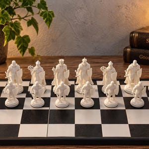 Könnte beinhalten: Ein Set weißer Schachfiguren auf einem schwarz-weiß karierten Schachbrett. Die Figuren umfassen Türme, Springer, Läufer, einen König und eine Königin, alle mit detaillierten mittelalterlichen Rüstungen, Umhängen und Schilden versehen.