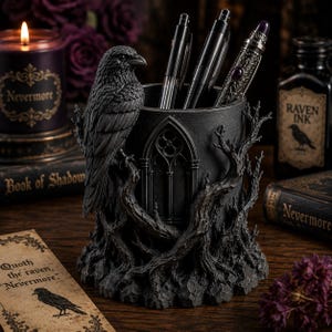 May include: A black cylindrical pen holder featuring a sculpted raven perched on a gnarled tree branch. The exterior is decorated with a gothic arched window design and textured roots at the base. Three pens are stored inside the container.