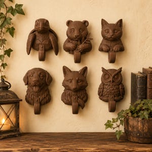 May include: A set of six brown wall-mounted hooks, each featuring a sculpted animal head. The collection includes a turtle, a panda holding a bamboo stalk, a cat, a dog with an open mouth, a fox, and an owl, all with a uniform matte finish.