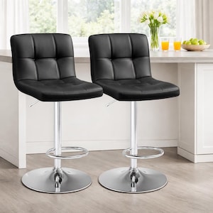 May include: Two black, square-stitched bar stools with chrome-finished bases and adjustable height mechanisms. The stools have a footrest and a circular base. The background includes a kitchen counter with a window and decorative items.
