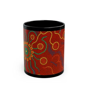 May include: A black coffee mug with a vibrant, colourful design. The mug features a red background adorned with a pattern of dots in yellow, green, and blue, forming a floral or sun-like motif. The rim and interior of the mug are black.