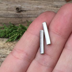 May include: A pair of silver bar earrings. The earrings are simple and minimalist, and they are perfect for everyday wear.