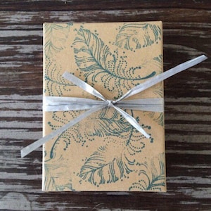 May include: A brown gift box with a blue and white feather pattern is wrapped with a silver ribbon.